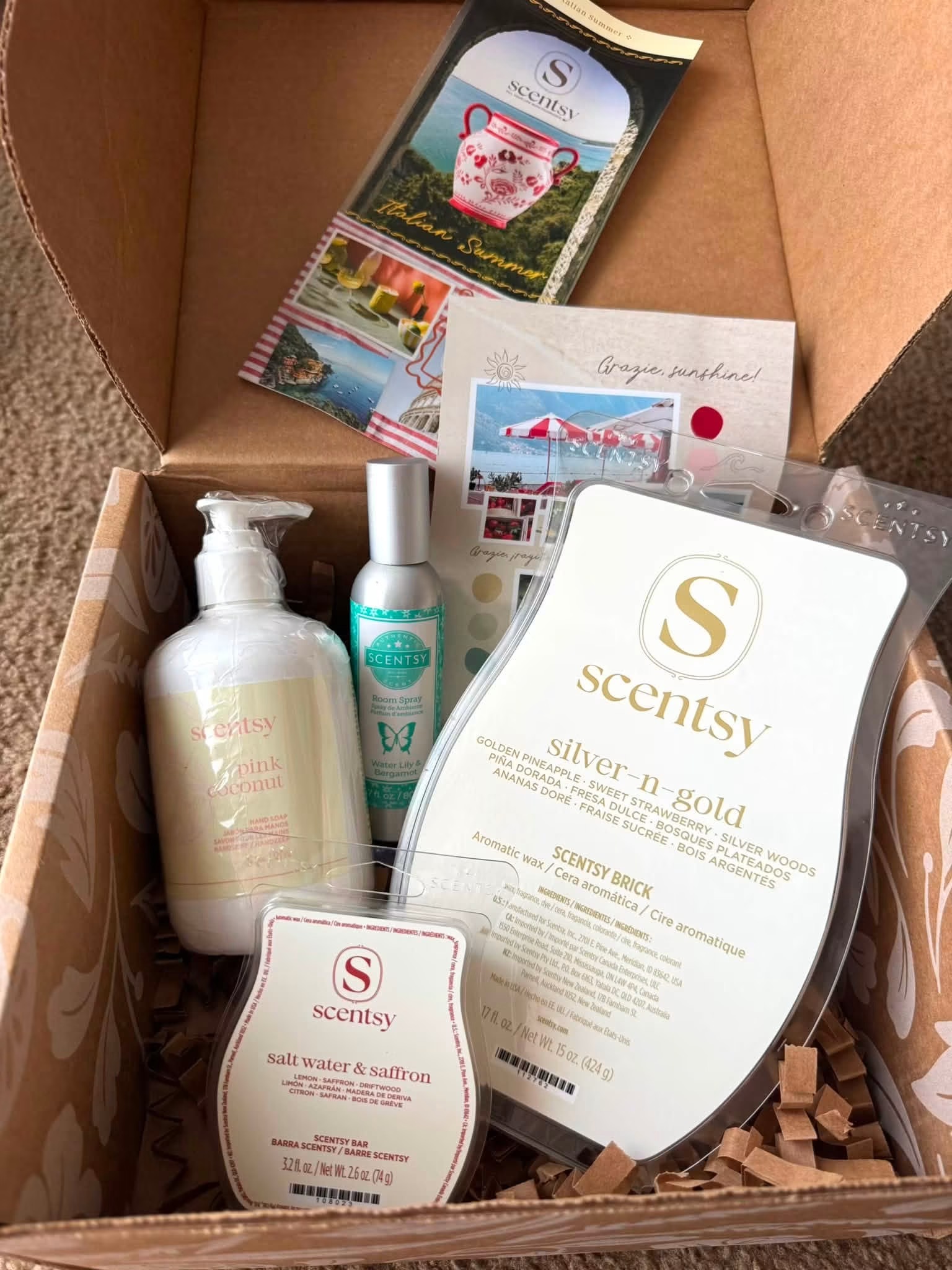 July Scentsy Whiff Box featuring Italian Summer themed products including Pink Coconut Hand Soap, Water Lily & Bergamot Room Spray, Salt Water & Saffron Scentsy Bar and Silver-n-Gold Scentsy Brick.
